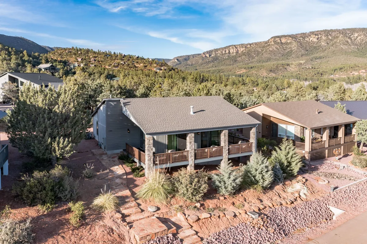 A welcoming porch overlooking natural landscaping and a mountain backdrop. The inviting outdoor space encourages morning coffee, family barbecues, and spotting local wildlife, embodying tranquil relaxation after a day of adventure.