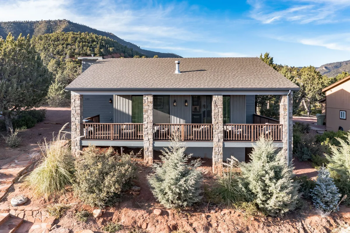 A welcoming front porch framed by stone pillars and surrounded by lush vegetation. The scene invites guests to relax, socialize, and enjoy the views—mirroring the inviting spirit of Pine’s downtown and its community gathering spots.